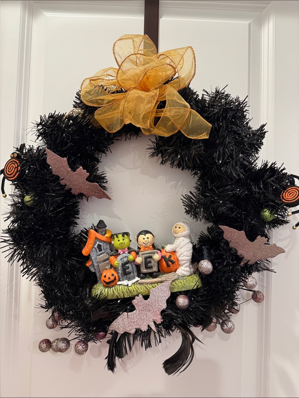 Black Halloween Wreath with Gold Bow and Trick-or-Treat Figurines